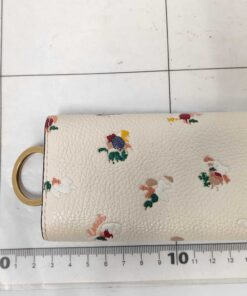 Back view of Coach floral key case positioned on a metric measuring grid.