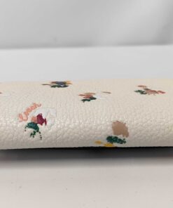 Bottom spine view of folded Coach chalk pebble leather floral key case.