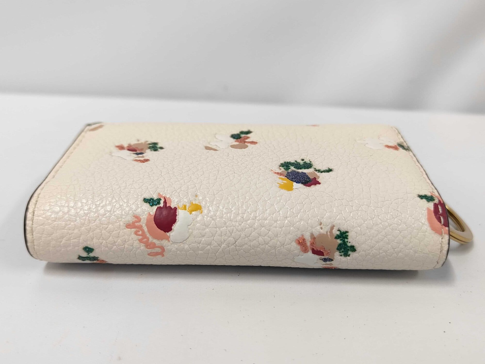 Opposite side profile of folded Coach floral trifold key case.