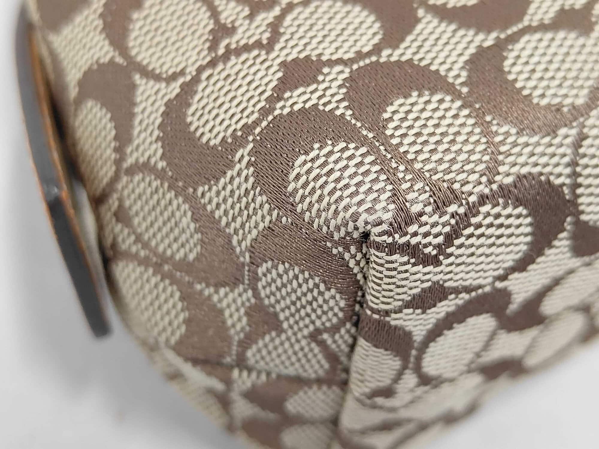 Close-up of bottom corner woven fabric on Coach signature pouch