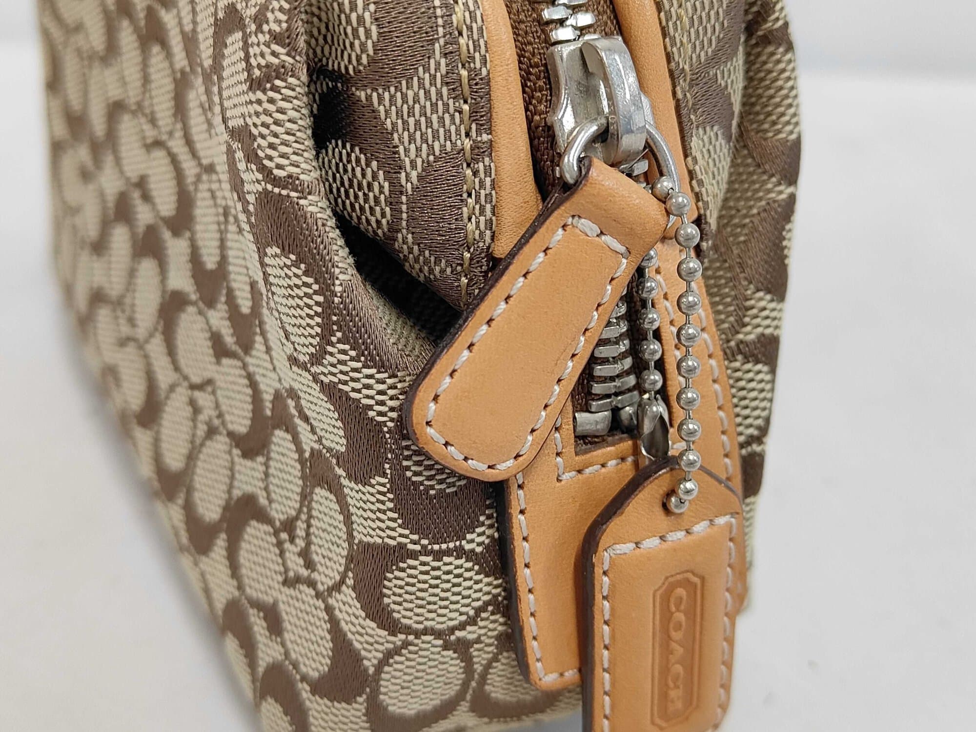 Side view showing silver-tone zipper, leather pull, and hangtag