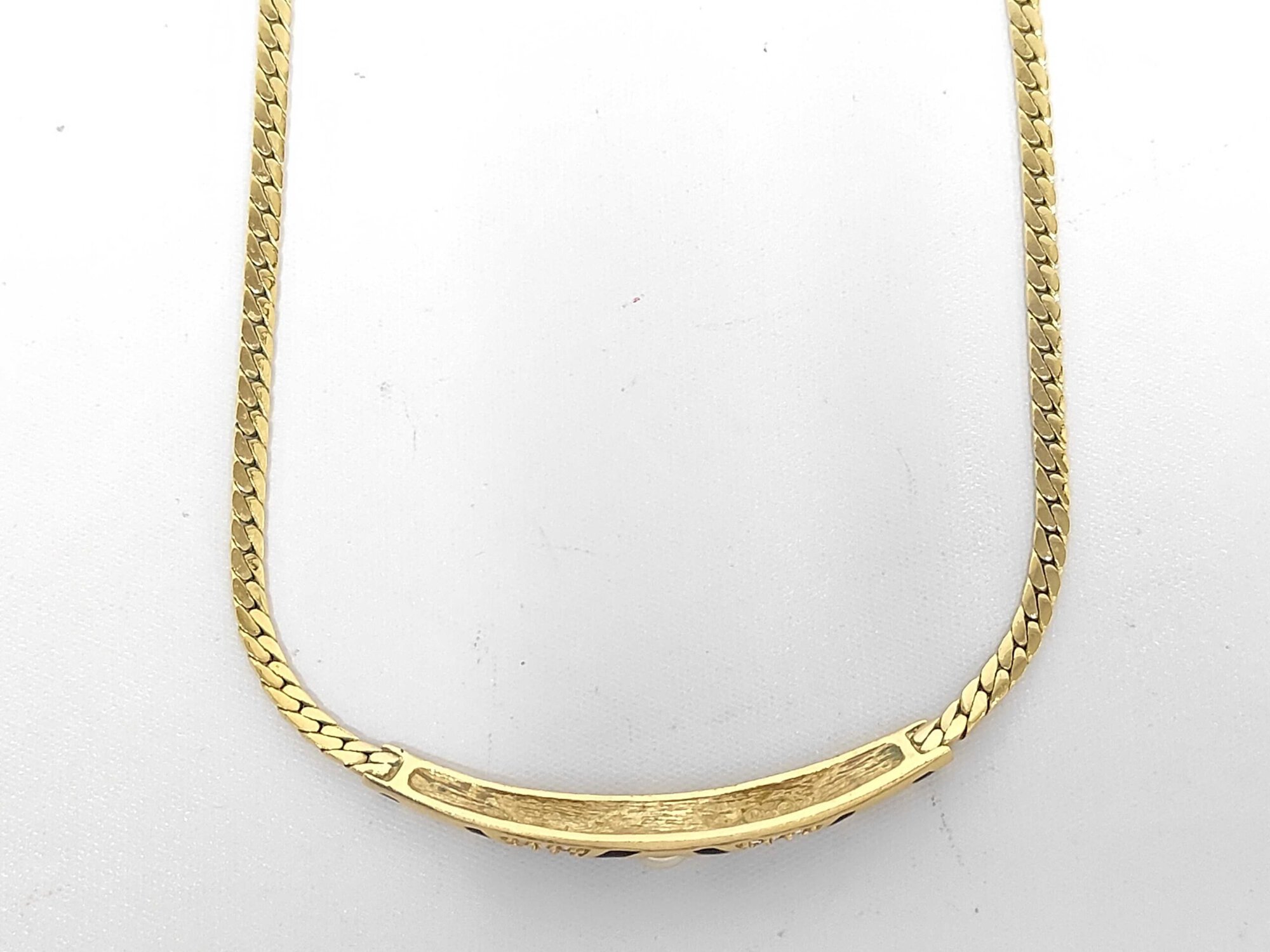 Reverse side of curved front station bar on gold-tone necklace.
