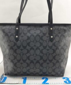 Rear view of Coach tote bag standing beside a base measurement ruler.