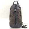 Front view of Coach dark brown nylon sling pack with black leather trim and vertical front zip.
