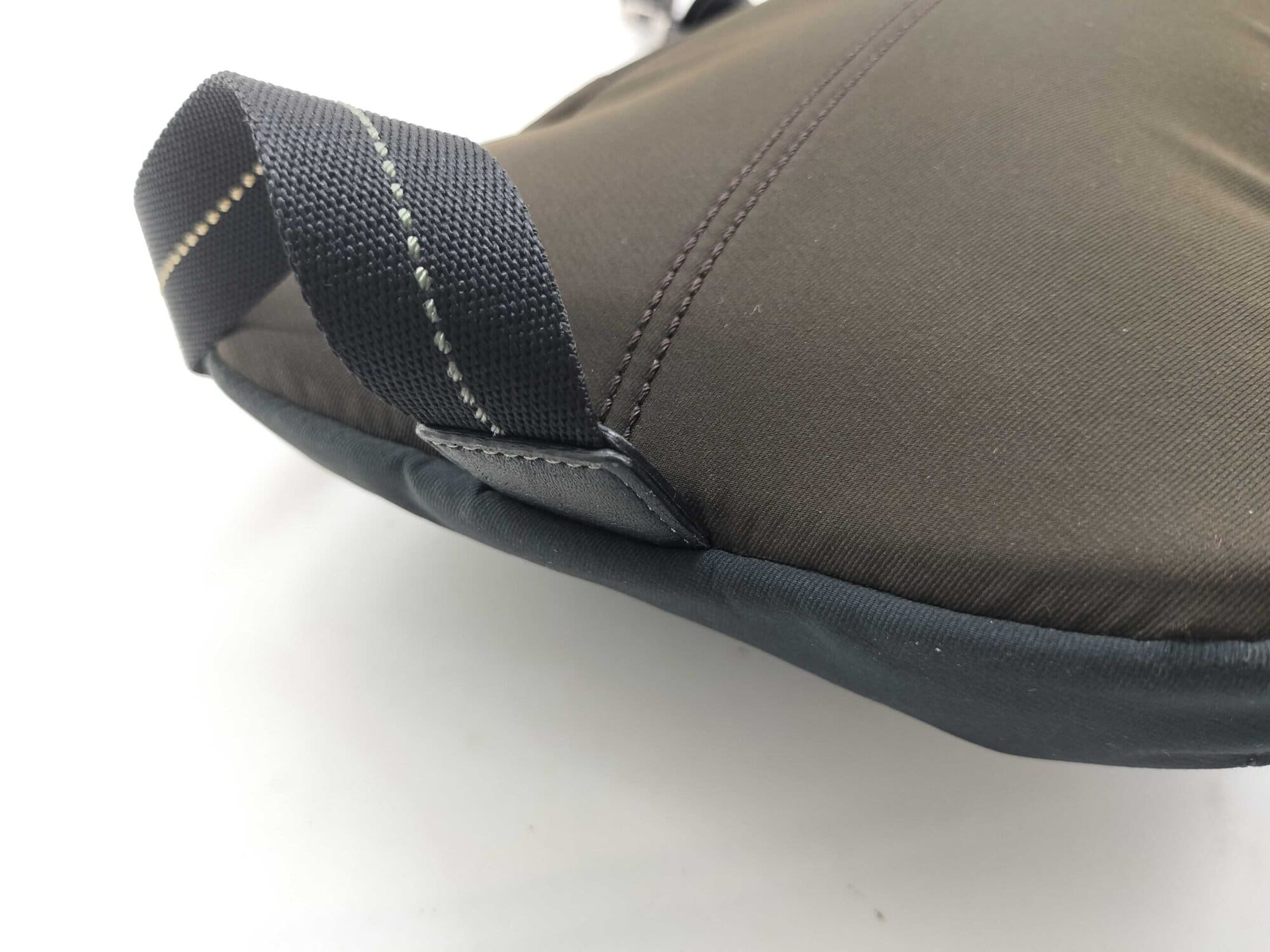 Side view of Coach sling pack showing dark brown nylon body and lower strap connection.