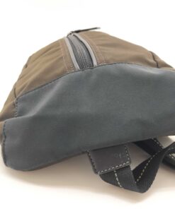 Underside view of Coach sling pack showing black textile base panel and webbing strap.
