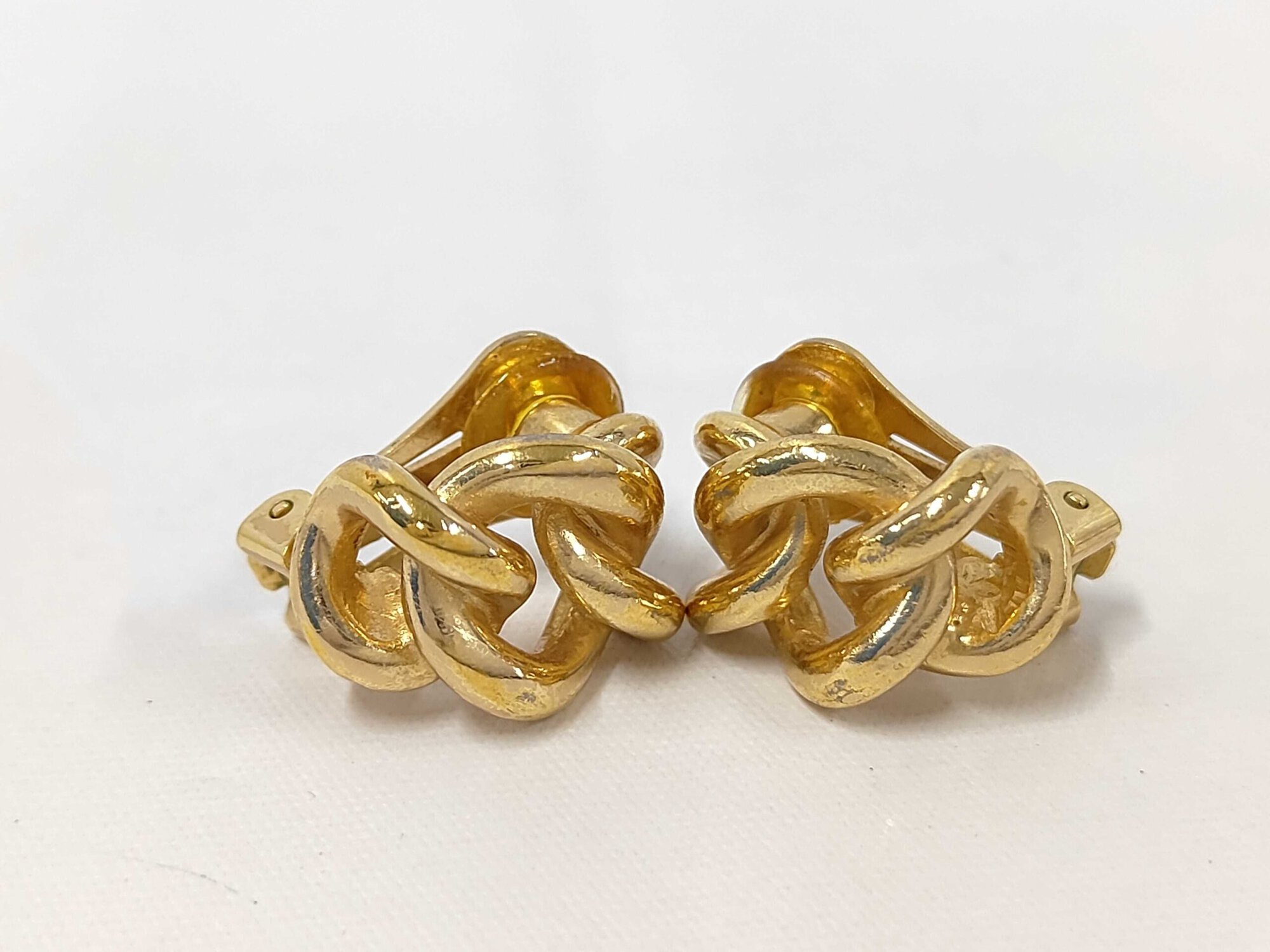 Front view of Christian Dior gold-tone twist knot clip-on earrings on a white surface.