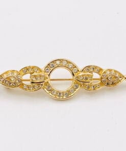 Front view of Christian Dior gold-tone horizontal bar brooch with open circle center and clear rhinestone accents.