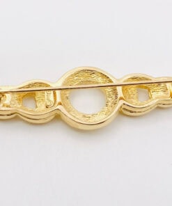 Back view of Christian Dior gold-tone bar brooch showing textured metal, horizontal pin stem, and rollover clasp.