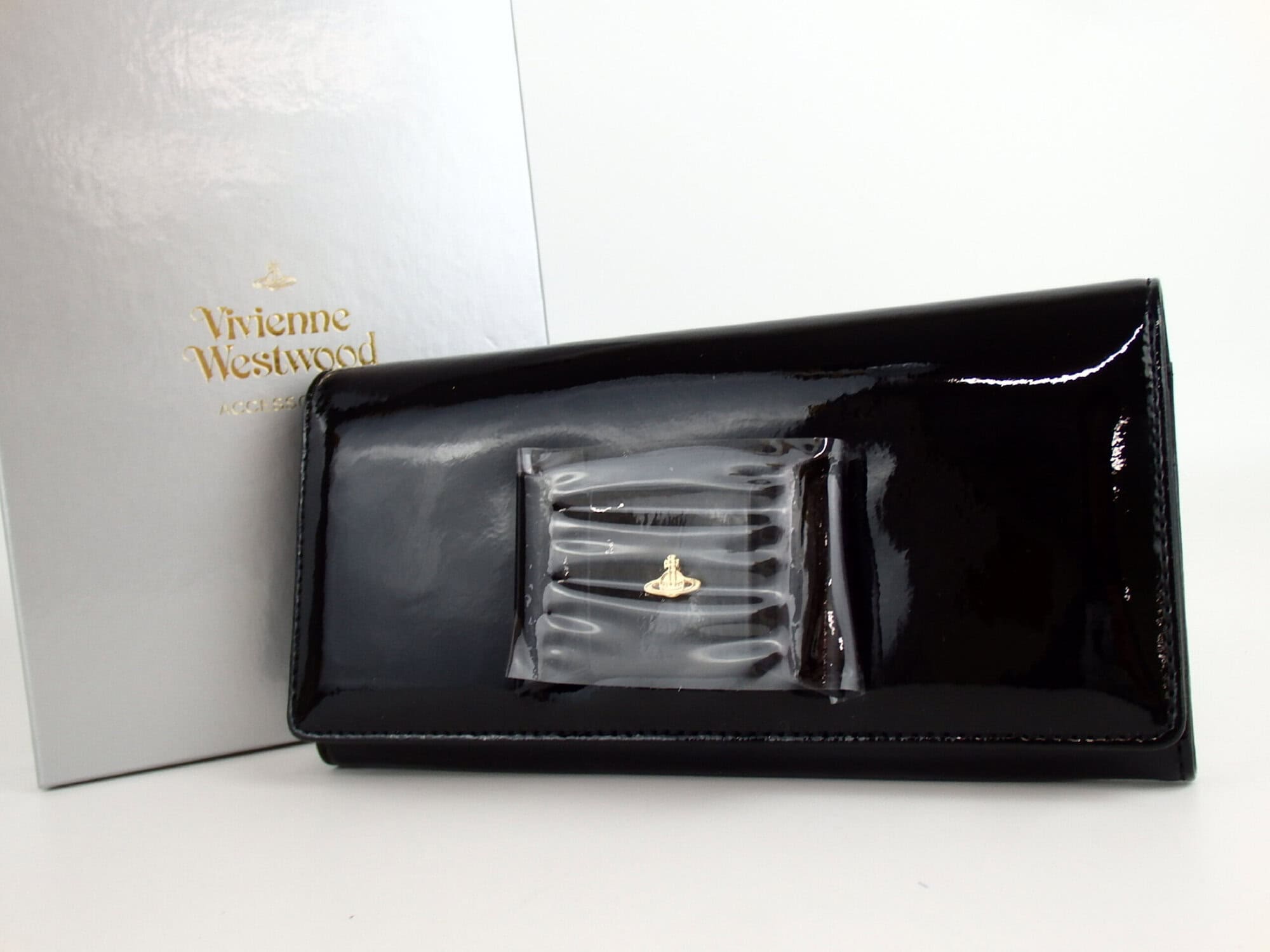 Front view of Vivienne Westwood black patent bow continental wallet with silver box