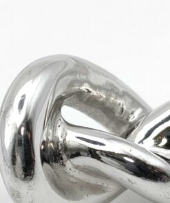 Macro front view of central sculptural knot motif on silver-tone bracelet