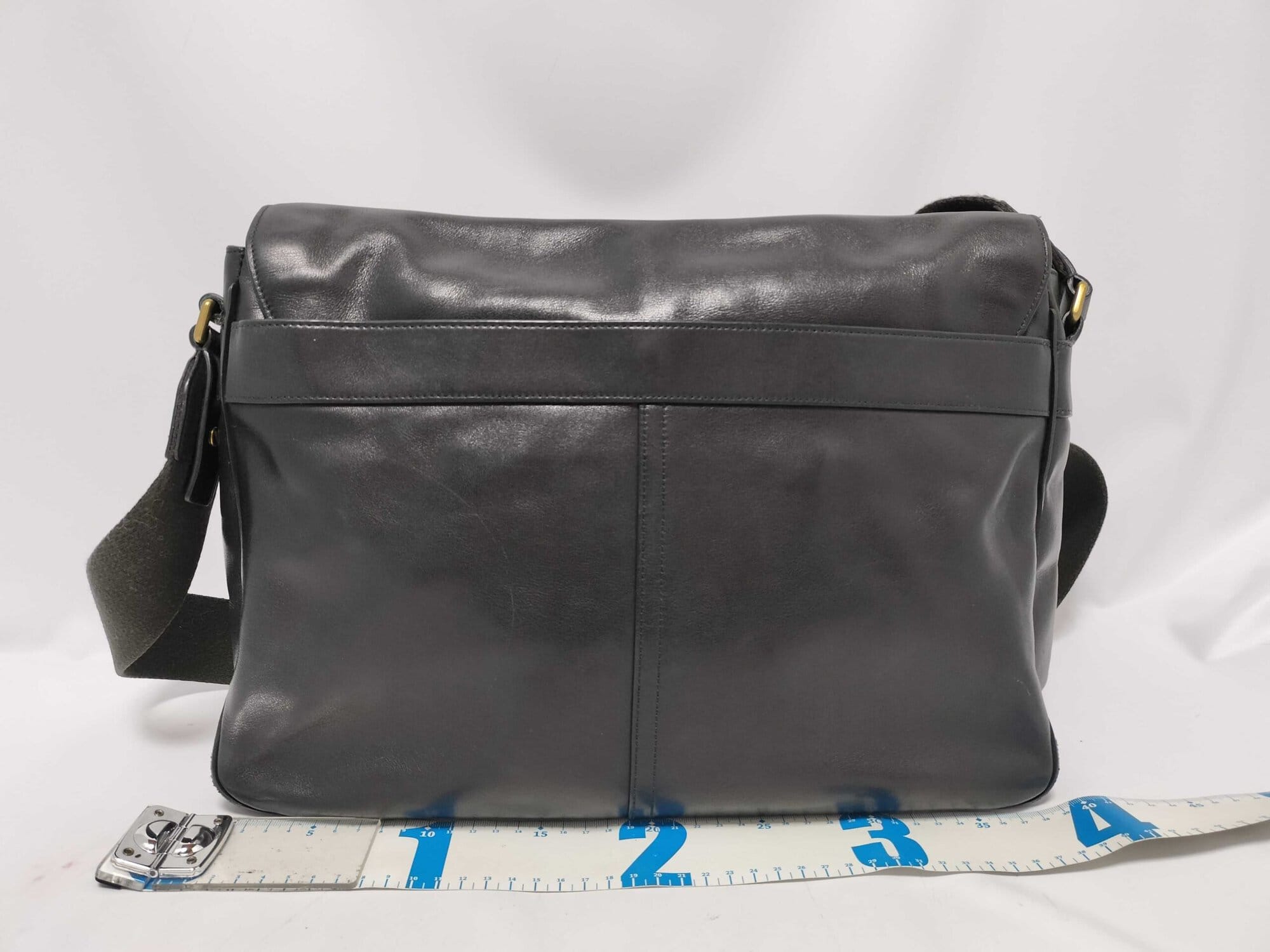 Rear view of Coach Bleecker messenger bag with tape measure showing width.