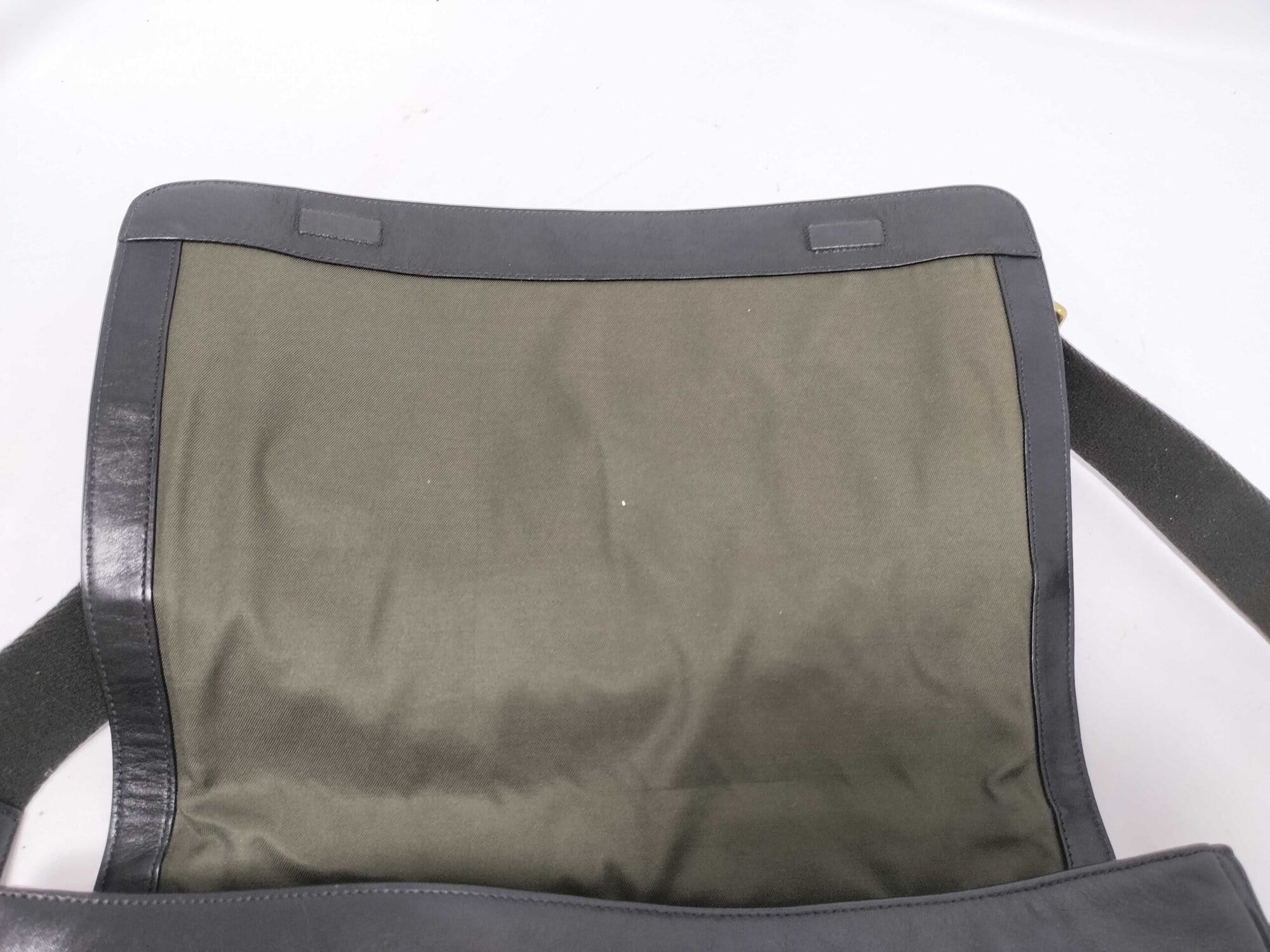 Underside of open front flap showing olive green fabric lining and magnetic snaps.