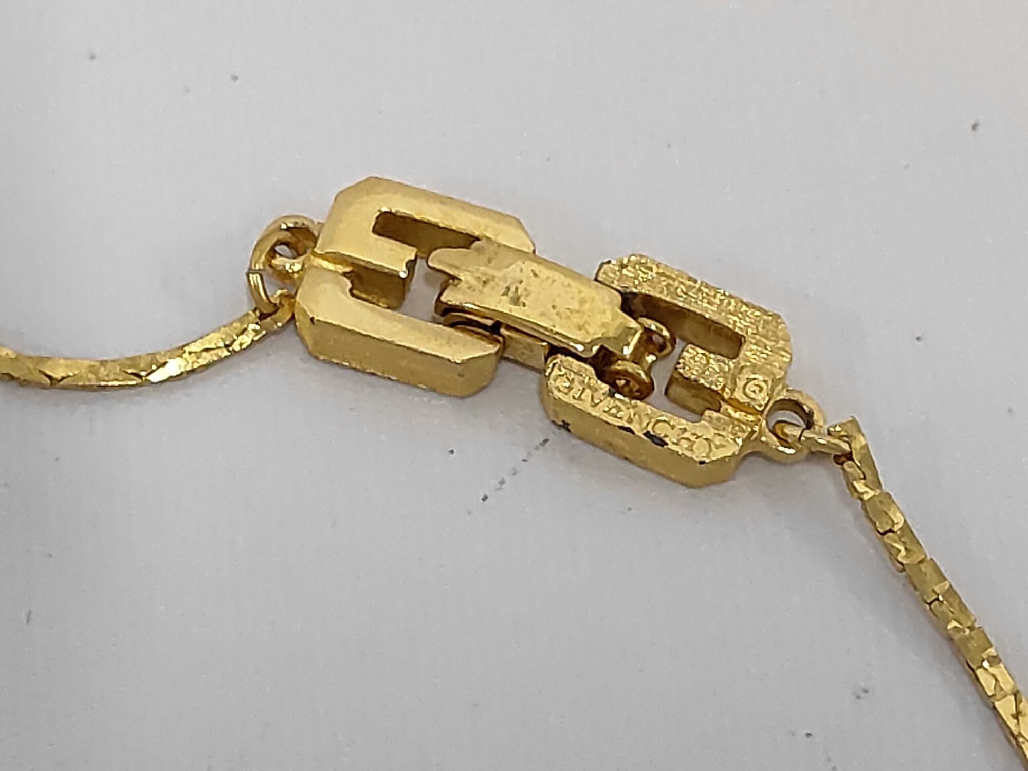 Givenchy gold-tone fold-over clasp mechanism showing embossed Givenchy signature and logo detail.