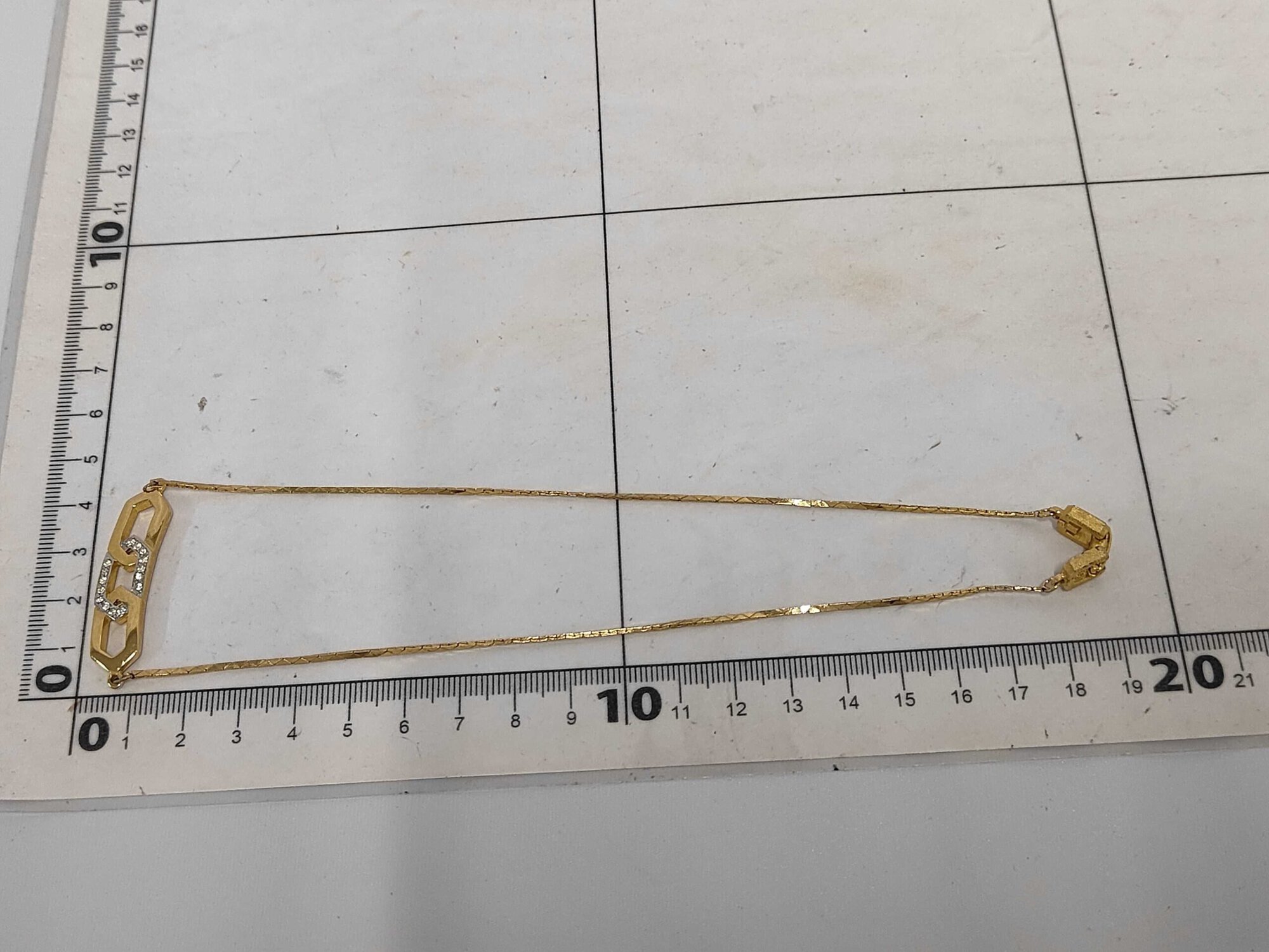 Givenchy necklace laid folded flat against a centimeter measuring grid mat.