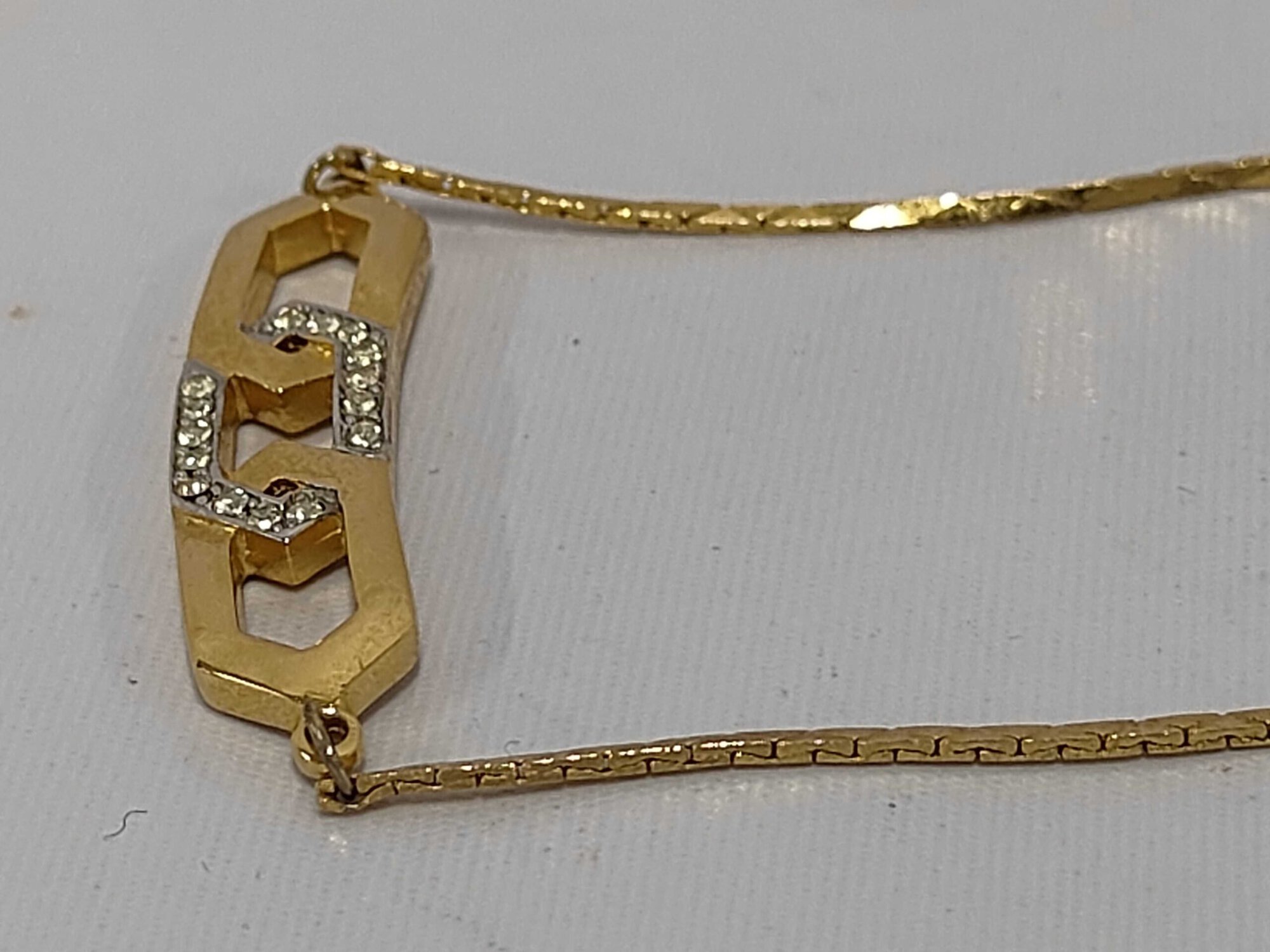 Angled view of Givenchy gold-tone necklace highlighting the dimensional links and clear stone settings.
