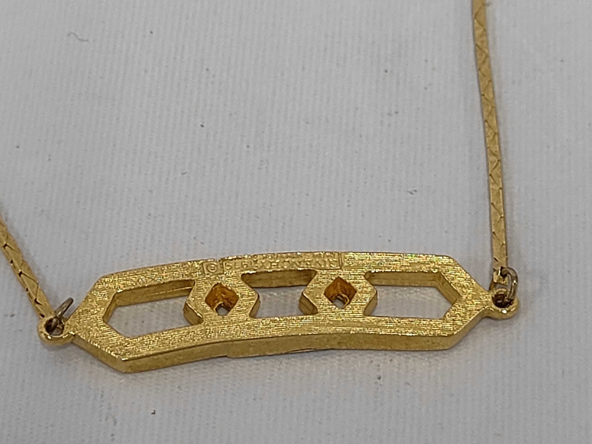 Reverse of Givenchy gold-tone hexagonal link necklace station showing brushed texture and hallmark.