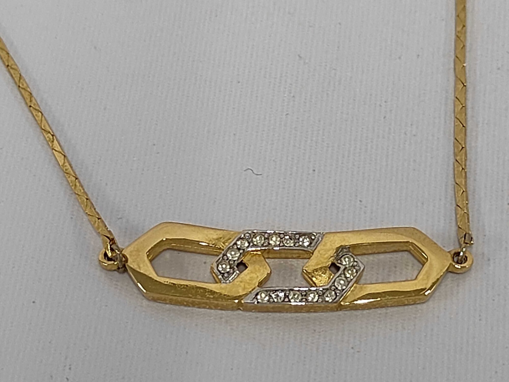 Givenchy gold-tone necklace featuring an interlocking hexagonal link motif with clear pavé accents on a flat chain.