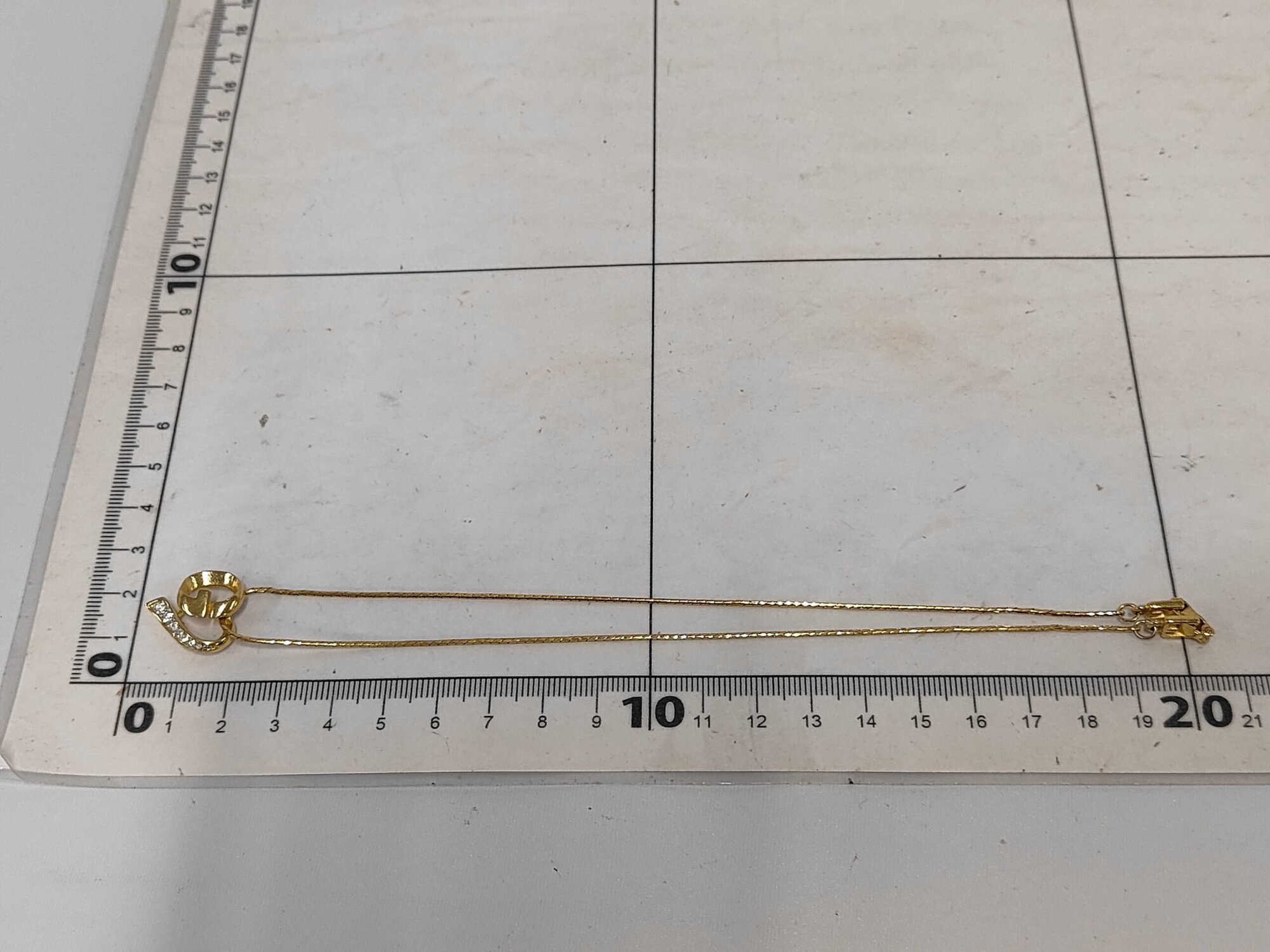 Givenchy necklace laid folded alongside measuring grid