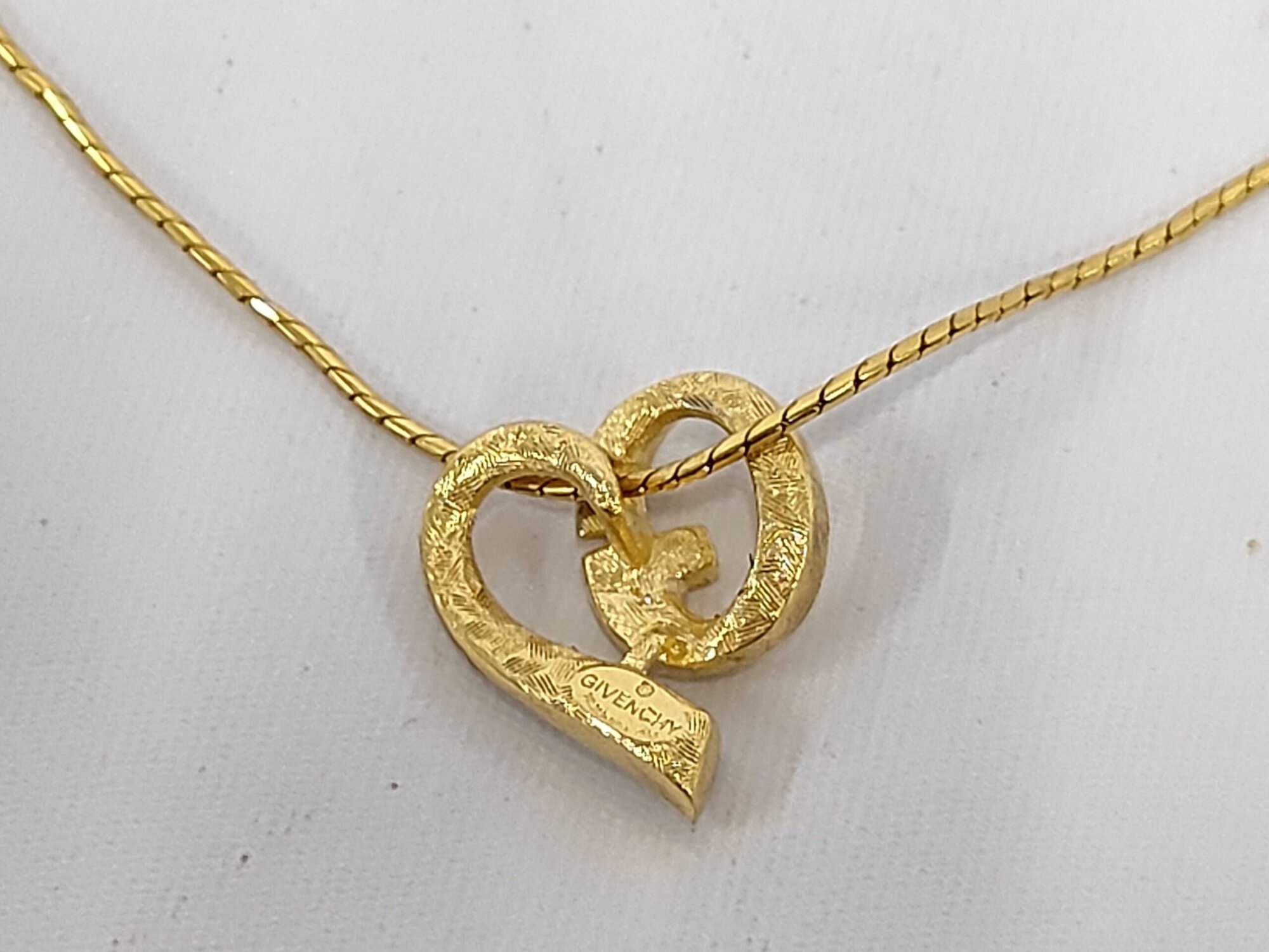 Back of Givenchy gold-tone asymmetrical heart pendant showing textured finish and hallmark