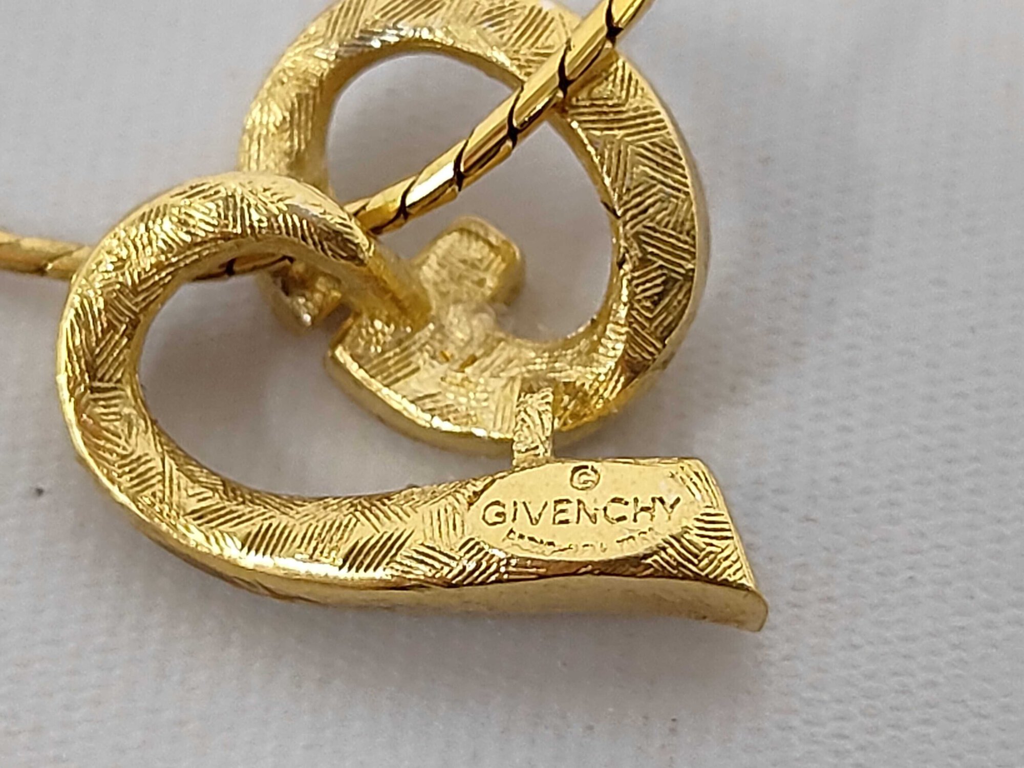 Close-up of stamped copyright Givenchy hallmark on back of gold-tone pendant