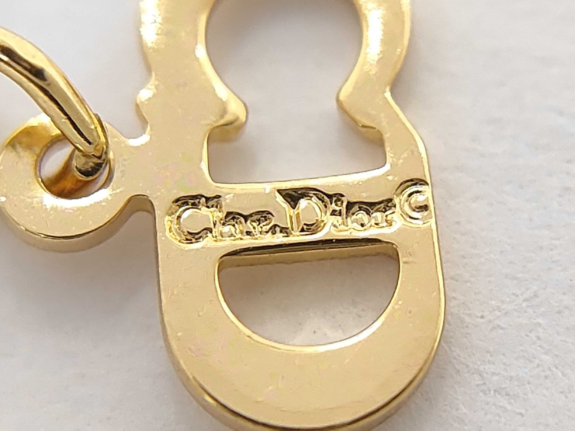 Close-up of the CD logo charm stamped with the Chr. Dior copyright hallmark.