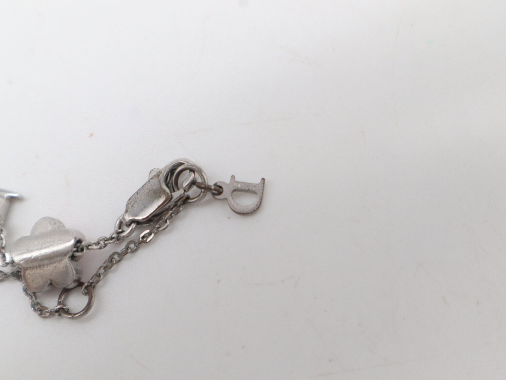 Close-up of the reverse side of the lobster clasp, extender chain, and engraved Dior letter charm.