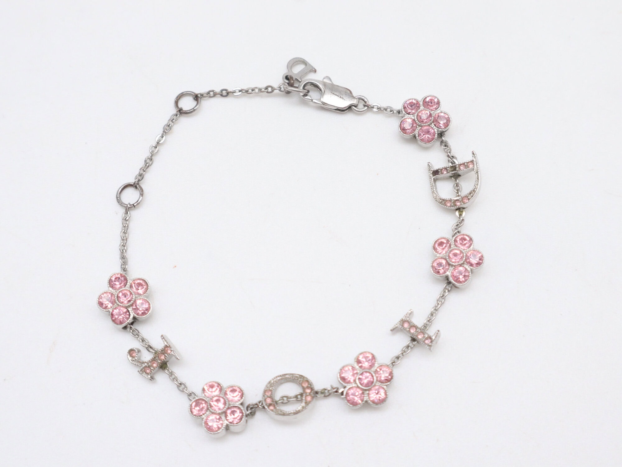 Christian Dior silver-tone charm bracelet arranged in an oval featuring pink floral stations and D-I-O-R letter charms.