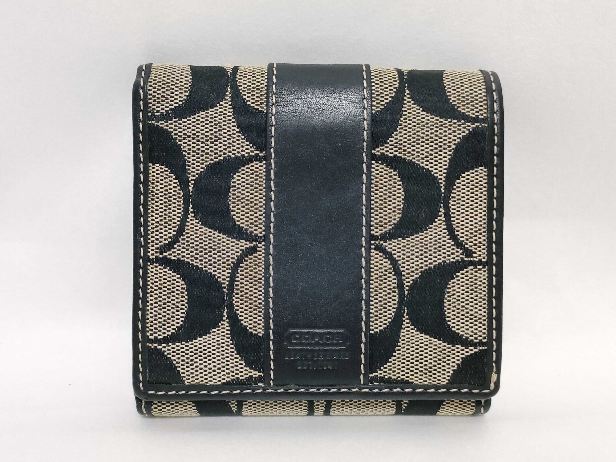 Front view of Coach Signature Stripe black jacquard and leather compact bifold wallet.
