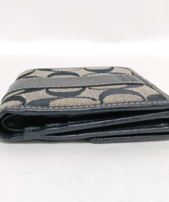 Side edge view of folded Coach bifold wallet showing thickness and layered construction.