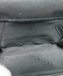 Interior overhead view of open coin pouch lined in black Coach-patterned fabric.