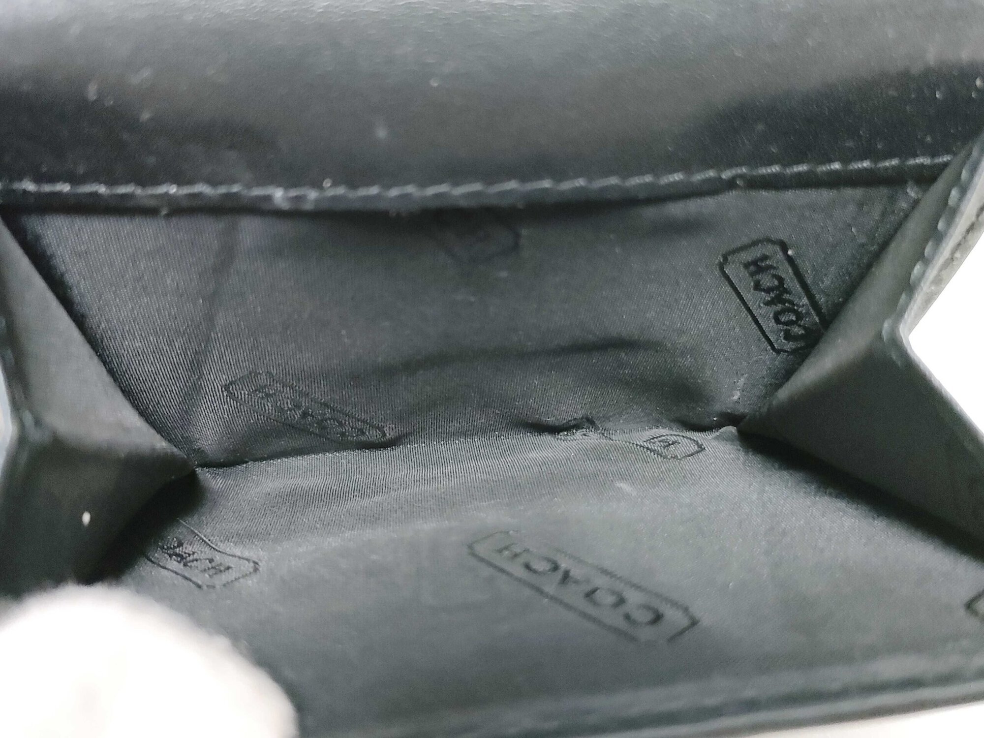 Interior overhead view of open coin pouch lined in black Coach-patterned fabric.