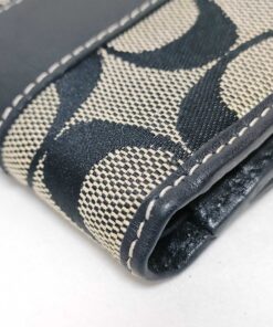 Close-up of corner edge binding and contrast white stitching on Coach bifold wallet.