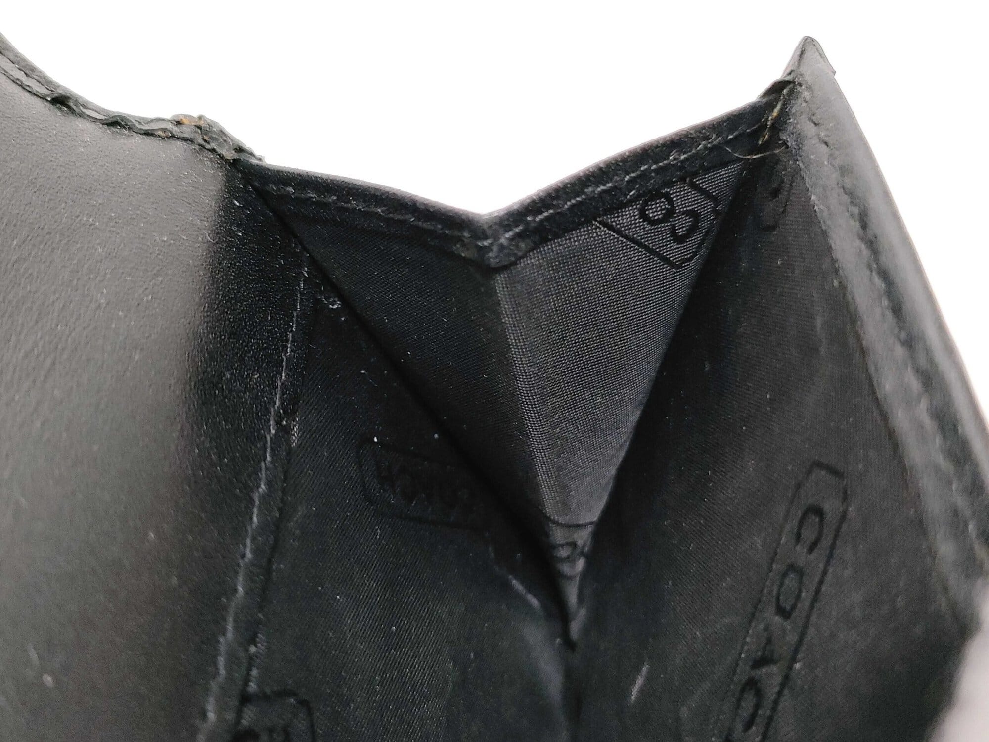Gusseted accordion coin compartment interior showing black Coach logo textile lining.