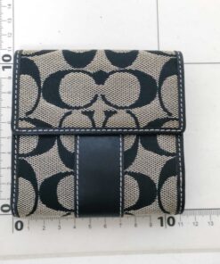 Back flap view of Coach compact bifold wallet positioned on a centimeter measuring grid.