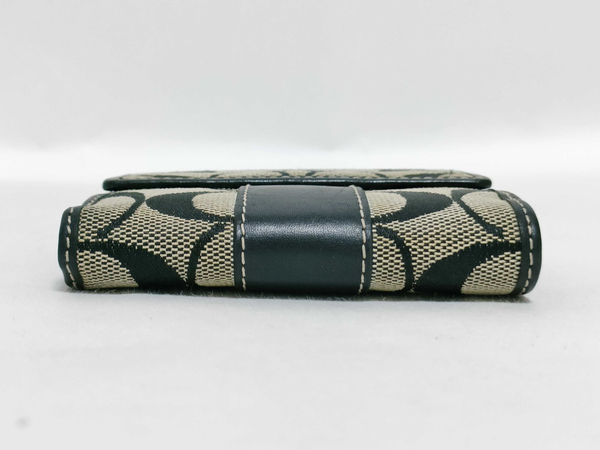 Bottom spine view of folded Coach Signature jacquard bifold wallet.