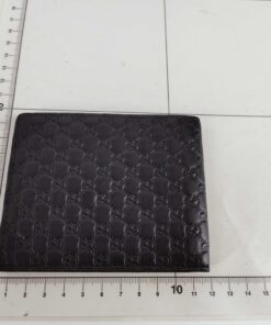 Gucci black leather bifold wallet displayed flat on a metric measuring grid
