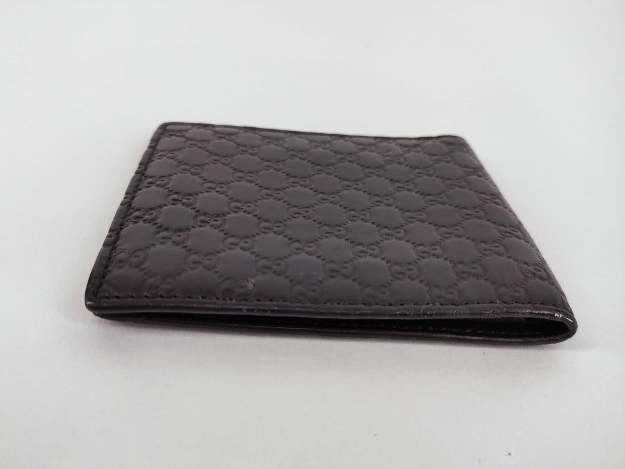 Opposite side profile of folded black Gucci Microguccissima leather bifold wallet