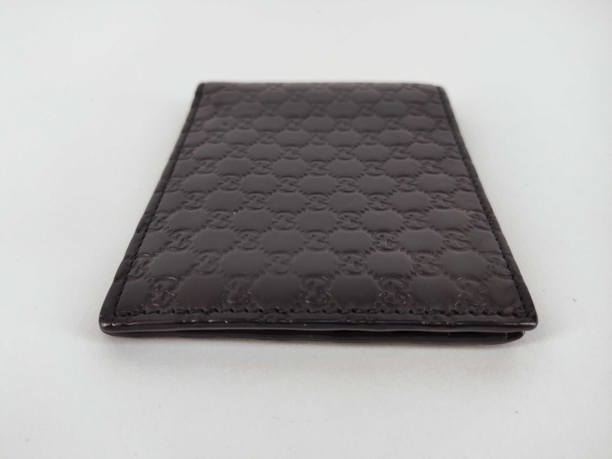 Bottom edge view of folded black leather Gucci Microguccissima bifold wallet