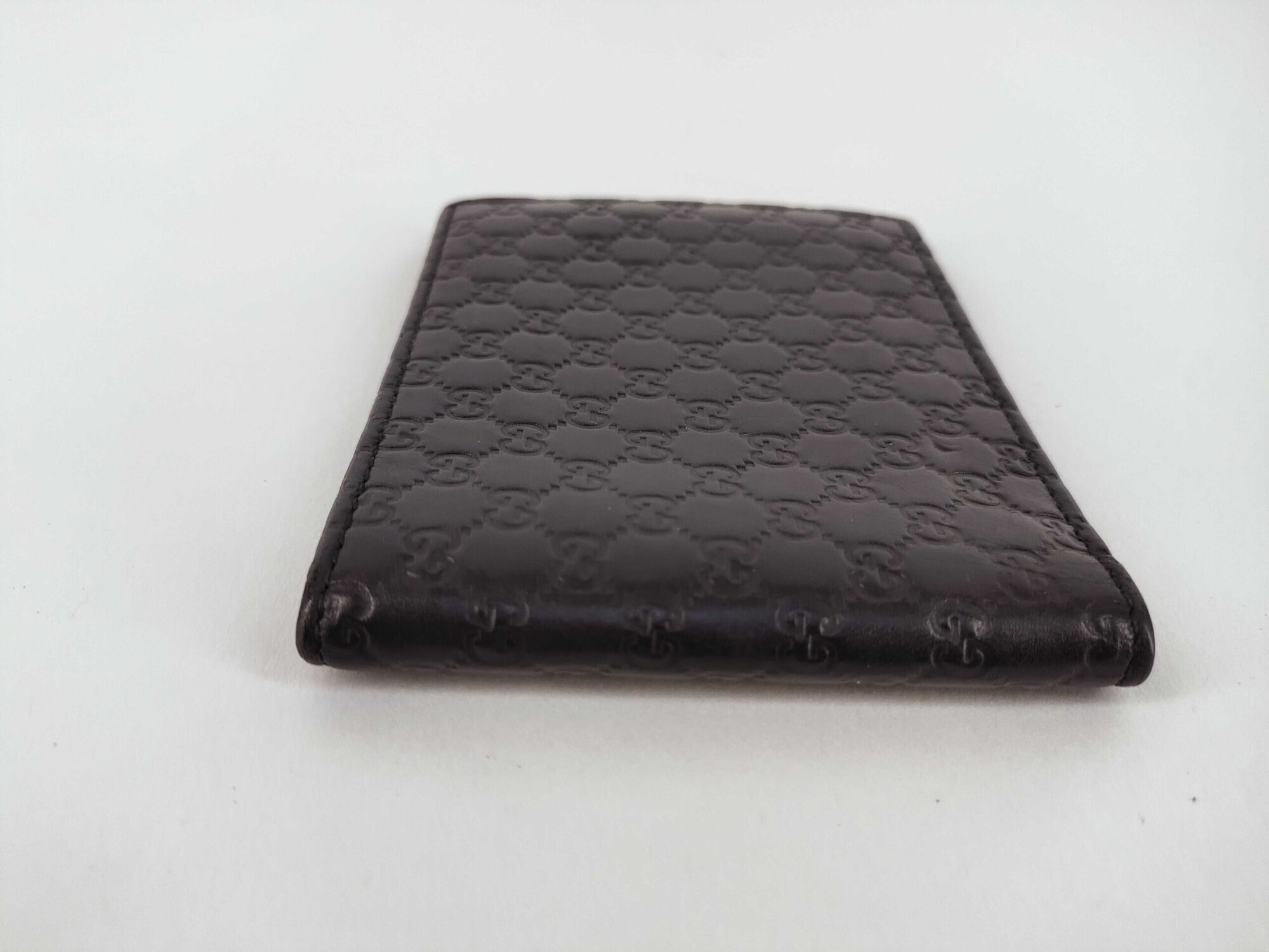 Side edge profile of folded black Gucci Microguccissima leather bifold wallet