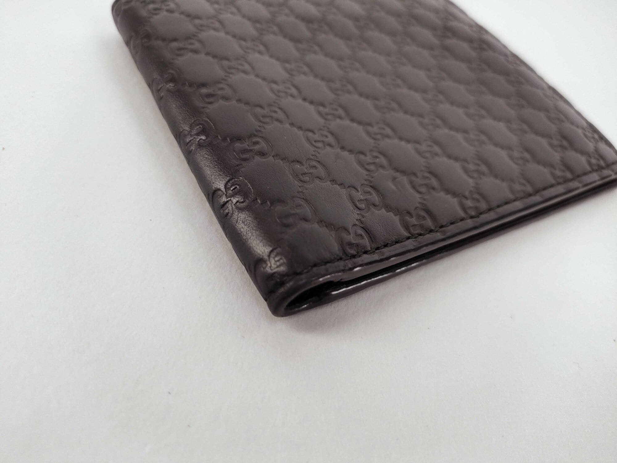 Angled view of folded Gucci Microguccissima black wallet spine and corner edge