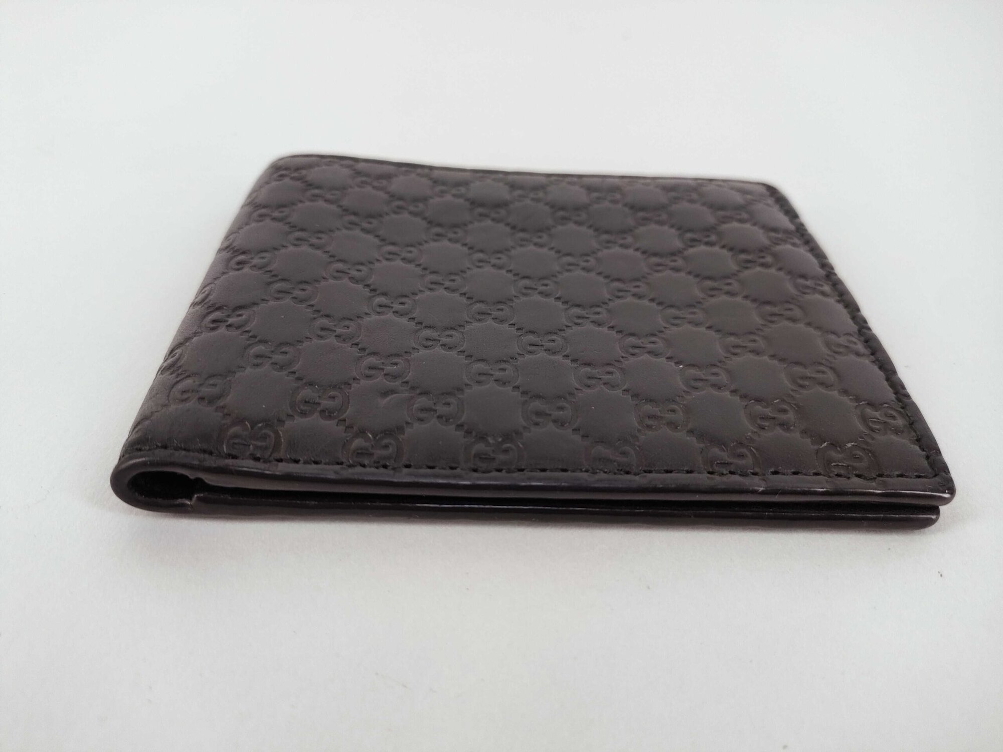 Top edge opening of folded black Gucci bifold wallet showing bill compartment