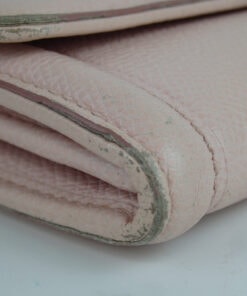 Close-up of bottom corner displaying edge rubbing and wear to the pink leather finish.