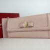 Salvatore Ferragamo light pink Vara bow continental wallet displayed with its red box and card holder insert.
