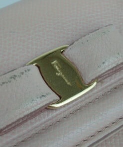 Close-up of the gold-tone Vara bow plaque and scuffed leather bow detailing on the front flap.