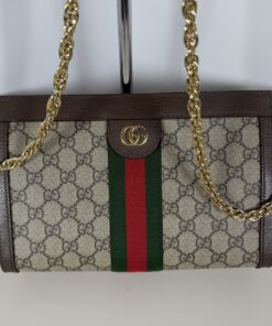 Authentic Pre-Owned Gucci chain shoulder bag in classic beige and ebony GG Supreme coated canvas. Highlighting the house's storied Italian luggage heritage, this elegant luxury accessory features a structured rectangular silhouette detailed by a striking green and red web stripe down the center. Anchored by an antique gold-tone interlocking Double G logo plaque and a fluid chain link strap, it delivers a timelessly chic statement from day to night