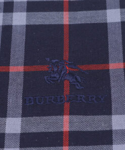 Close-up of navy embroidered Burberry Equestrian Knight logo on check cotton fabric.
