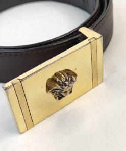 Close-up of gold-tone rectangular buckle with raised Medusa head emblem.