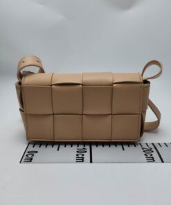Front view of Bottega Veneta Mini Cassette bag in almond beige leather beside metric ruler.