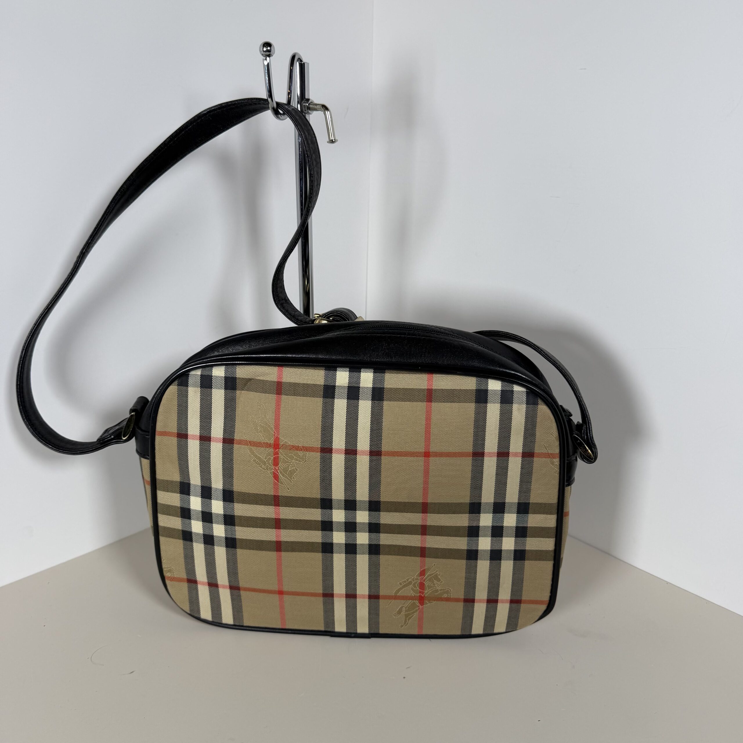 Back view of Burberrys Haymarket check canvas crossbody bag showing black leather piping.